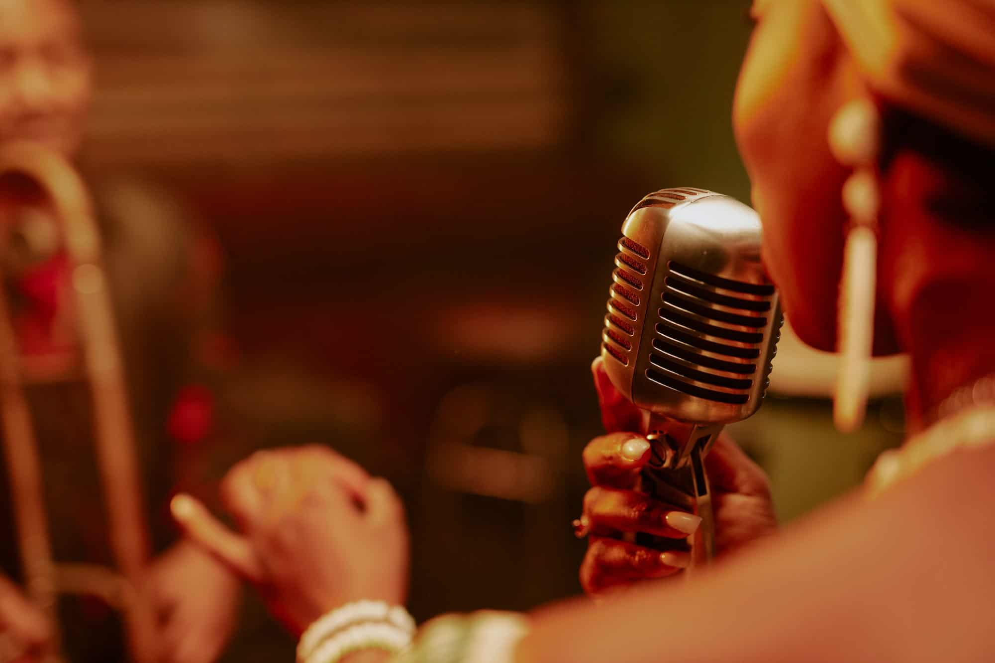 Woman wearing jewelry while singing into a microphone and performing live