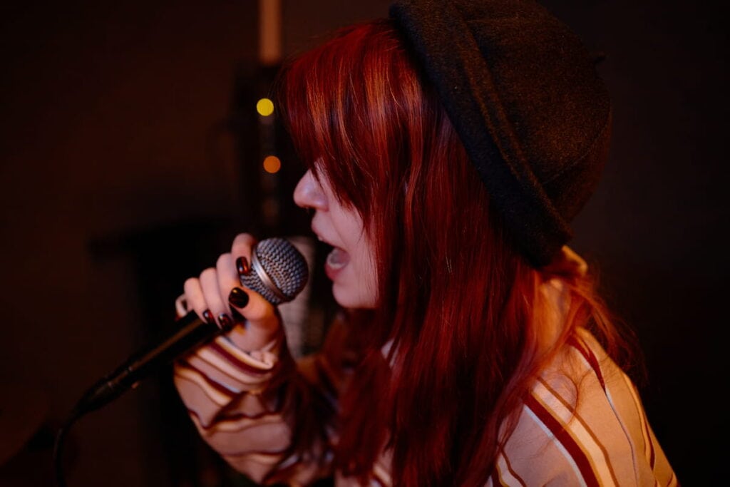 Female singer with red hair singing a song into a microphone