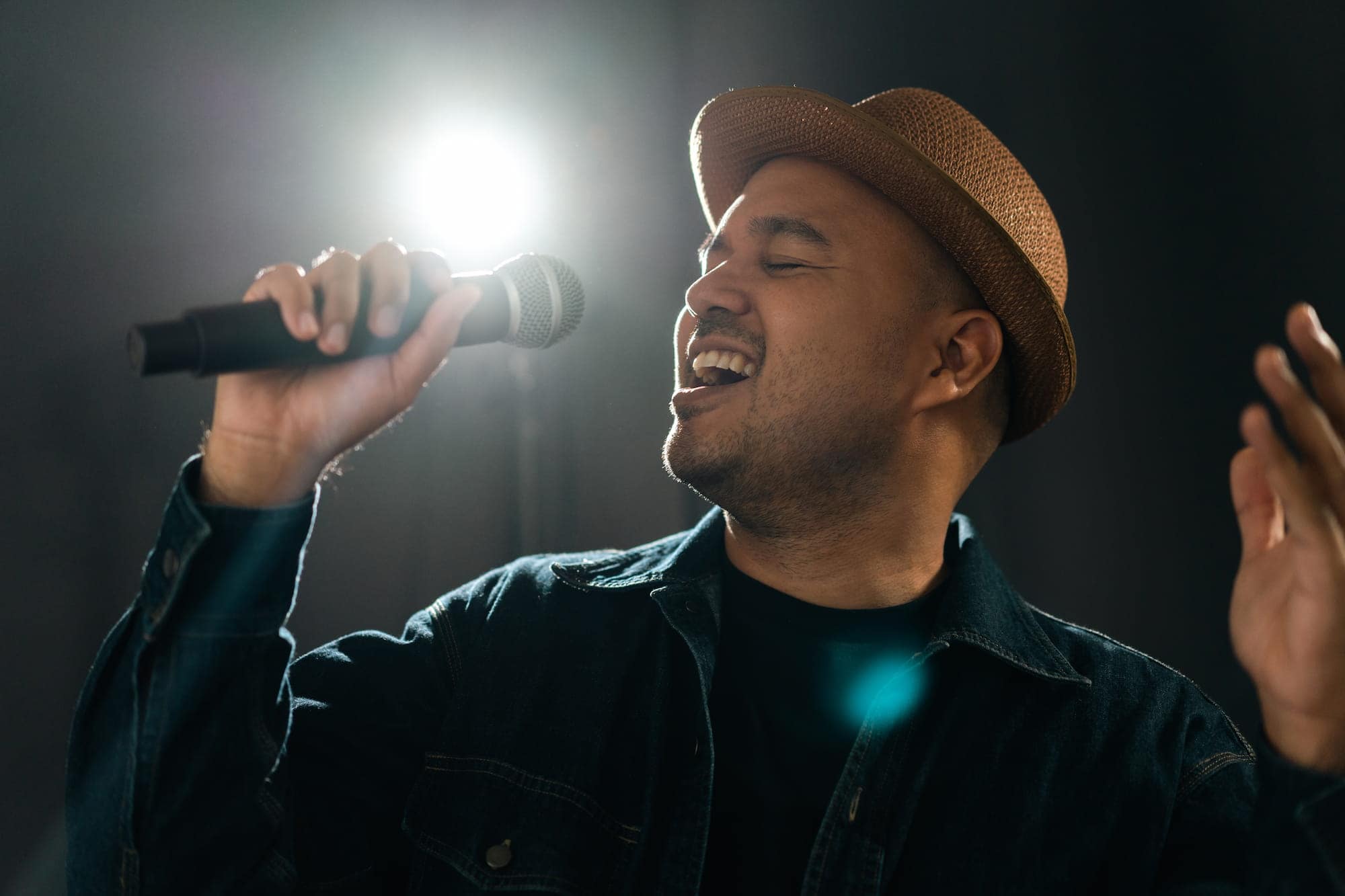 Man wearing a hat and singing into a microphone