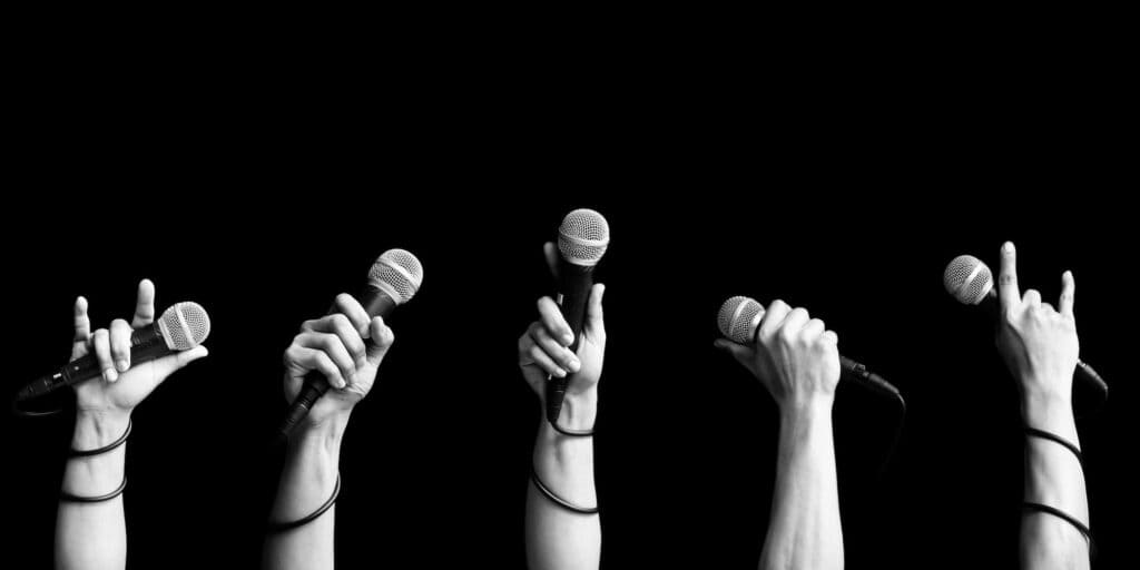 People holding up microphones with a dark background