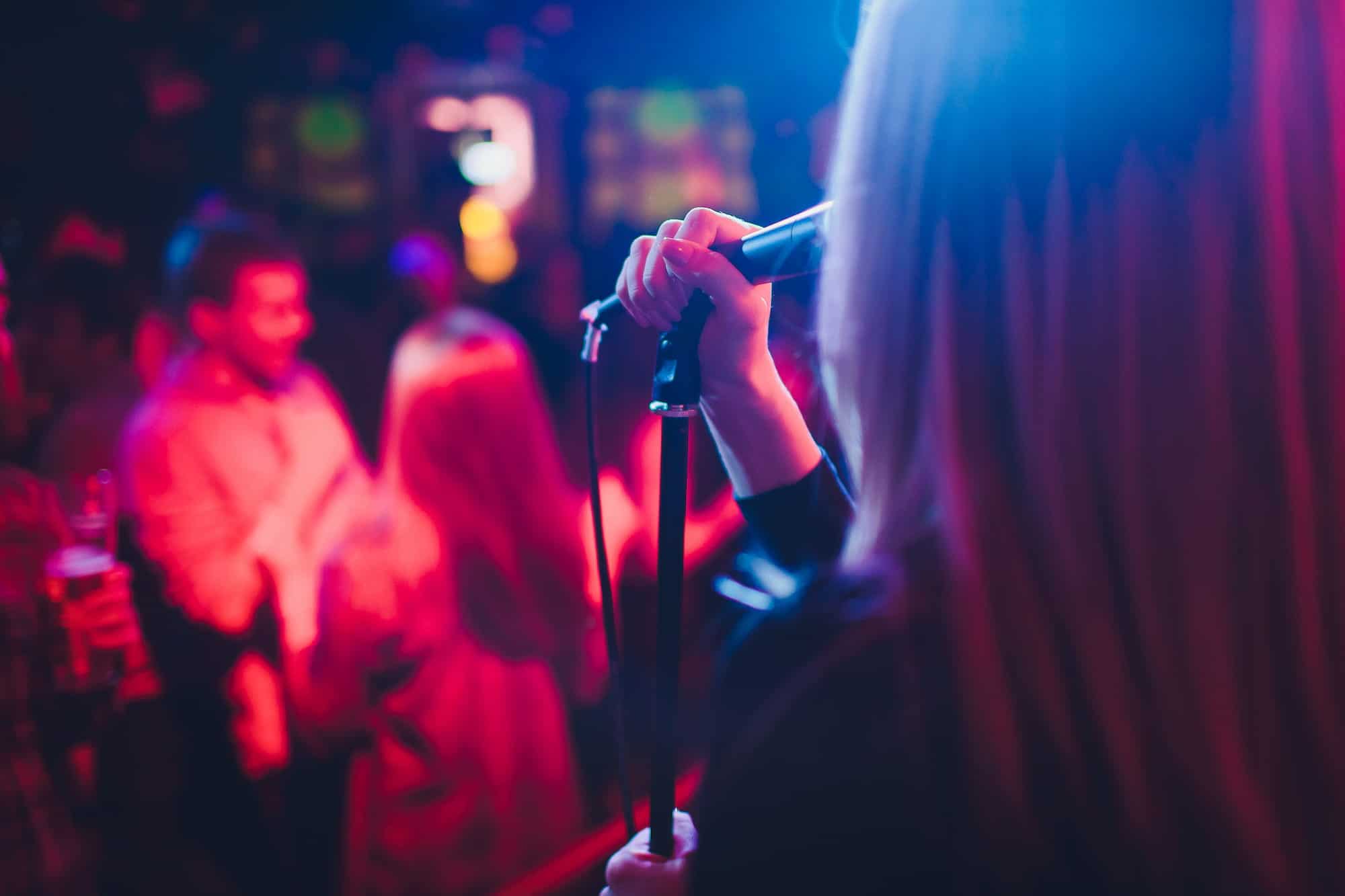 Woman singing on a microphone at a bar